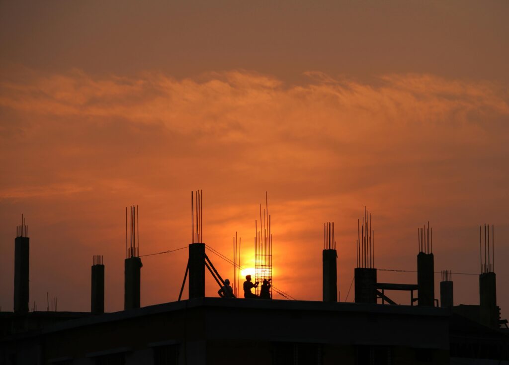 pexels-photo-176342-176342 Silhouette of workers on a construction site against a vibrant sunset sky.